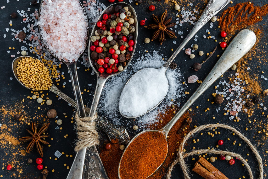 A table topped with spoons filled with different spices.